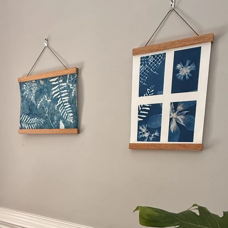 A framed cyanotype fern print hanging on a wall