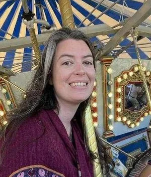 Jenna, the wax sealing instructor, smiling in front of a carousel